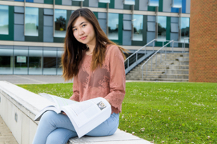Priscilla Bang sitting outside, holding a textbook