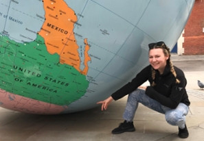 Sarah Noyce crouching in front of a giant globe